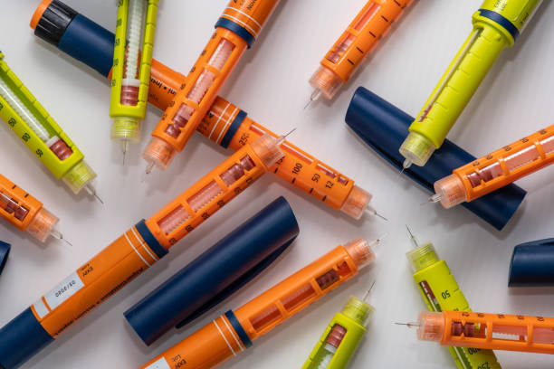 Close up of a stack of used insulin syringes in bright yellow and orange color, used by diabetics to insert insulin under the skin